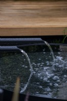 Water flowing from black metal spouts into a pond - The Calm of Bangkok, RHS Chelsea Flower Show 2021