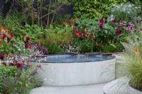 Copper water rills feeding into a raised pond with colourful planting behind, including Echinacea 'Eccentric', Persicaria amplexicaulis 'Firedance', Dahlia, Kniphofia and Echinacea purpurea - Finding Our Way: An NHS Tribute Garden, RHS Chelsea Flower Show 2021