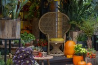 Wicker chair surrounded by an Autumn arrangement with pumpkins and candles
