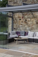 corner rattan sofa piled with cushions in the conservatory