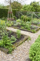 Kitchen garden with raised beds of herbs and plant supports made from willow and hazel.