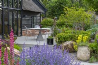 A small contemporary raised deck is edged in a border of multi-stemmed amelanchier, low hornbeam hedges and perennials.