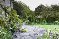 Terrace in a country garden in May with borders of yew pyramids.
