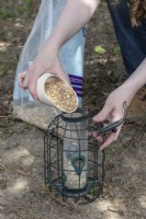 Woman filling bird feeder with mixed seeds and grains