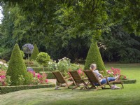 Woman relaxing on wooden sun lounger in Swafield Hall Gardens Norfolk