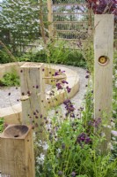 Wildlife area with wooden bird-feeder with seeds on spoons among perennials with Penstemon, Sanguisorba and Gaura  in  The Wooden Spoon Garden, RHS Hampton Court Palace Garden Festival 2022