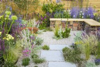 Low maintenance gravel garden with gabion bench, Corten steel water bowl and drought tolerant plants to attract pollinators, such as Salvia, Achillea, Echinops, Perovskia and Gaura surrounded by contemporary fencing - Turfed Out Garden, RHS Hampton Court Palace Garden Festival 2022