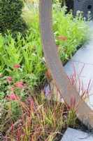 Planting of imperata cylindrica 'Red Baron' grasses with Corten steel moongate detail - Sunburst Garden, RHS Hampton Court Palace Garden Festival 2022  
