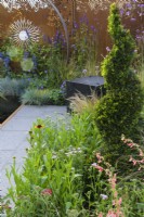 Corten steel panels enclosing planting of spiral Yew topiary with   Penstemon barbatus 'Roseus' and Achillea 'Paprika' - Sunburst Garden, RHS Hampton Court Palace Garden Festival 2022