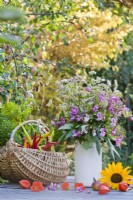 Basket with harvested vegetables and flower bouquet containing Impatiens glandulifera and Fagopyrum esculentum.