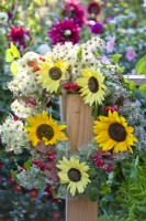 Floral wreath made of Clematis, sunflowers and rowan's berries hanging from the edge of the table.