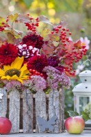 Late summer floral display with sunflowers, sedum, dahlias and guelder rose branches with berries on the table.