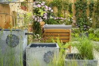 Three lead-effect containers used as a cascading water feature with planting - Knolling with Daisies, RHS Hampton Court Palace Garden Festival 2022