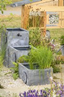 Three lead effect square containers used as a cascading water feature with planting of ferns and grasses - Knolling with Daisies, RHS Hampton Court Palace Garden Festival 2022