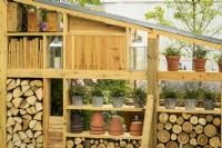 Wooden modular wall storage and display made from reclaimed timber with logs and Erigeron karvinskianus 'Profusion' - Mexican fleabane in containers in knollingwithdaisies garden at RHS Hampton Court Palace Garden Festival 2022
