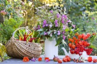 Floral arrangement and harvested vegetables on the table including buckwheat, Himalayan balsam, Chinese lanterns and rowan berries.