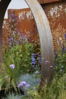 Corten steel garden feature and backdrop panels with mixed colourful planting. The Sunburst Garden. Design: Charlie Bloom and Simon Webster. RHS Hampton Court Garden Festival 2022.