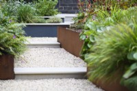 Gravel path with steps and raised corten steel beds. 