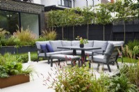 Seating area surrounded by raised flowerbeds and pleached trees. 