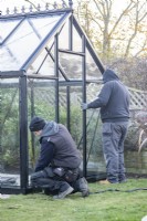 Men placing glass in the greenhouse