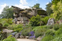 Naturalistic planting around dramatic rock formations in Paxton's Rock Garden, Chatsworth House and Garden.