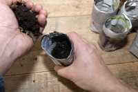 Making planting pots for seedlings from old newspapers. 
Compost is added to newly made homemade plant pots created using old newspapers.