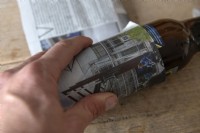 Making planting pots for seedlings from old newspapers. 
Two pages of a tabloid size newspaper first cut into three strips and with the leading edge folded is rolled over a 30cl beer bottle to create a tube. 