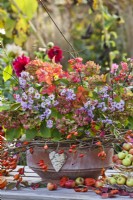 Terracotta pot decorated with rose hip wreath and filled with hydrangea, asters, guelder rose and euonymus.