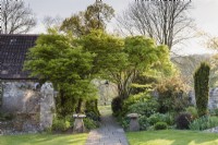 Stone path leading into a country garden in April, framed by a pair of staddle stones