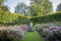 Border of mixed roses with stone statue as focal point in the David Austin Rose garden