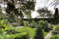 Country garden in September with a mix of clipped evergreens, perennials and tender plants such as pelargoniums in containers.