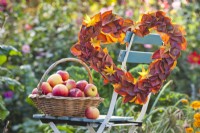 Heart shaped wreath made of maple  and persimmon leaves and harvested apples.
