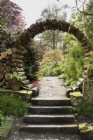 Moon gate made from logs at the entrance to the flower garden at Enys gardens, Cornwall in early May.