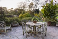 Terrace with timber seating surrounded by foliage plants at John Massey's garden in October.