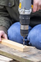 Woman drilling holes in the ends of the pieces of wood