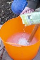 Woman pouring rootgrow granules into the solution