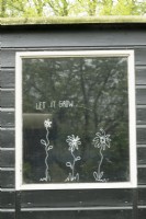 Flower drawings and Let it grow written on window.