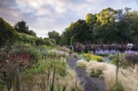 Path through Stipa tenuissima edging densely planted borders at Whitburgh Walled Garden in Scotland in September