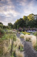 Path through Stipa tenuissima edging densely planted borders at Whitburgh Walled Garden in Scotland in September