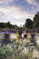 Border of ornamental grasses, tender perennials, annuals and decorative vegetables at Whitburgh House Walled Garden in September including Stipa tenuissima, salvias, dark Kale 'Redbor' and ricinus.