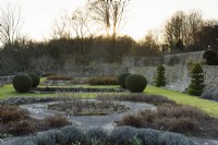 The Jewson Terrace at Cotswold Farm Gardens in February with geometric beds and clipped evergreens including yew and box.