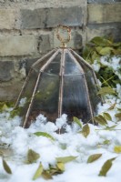 Cast iron and glass octagonal lantern cloche next to brick wall with snow. December.