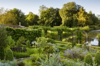 View across the herb garden and 12th century moat to pasture beyond. In the foreground is artichoke Cynara scolymus, a standard bay Laurus nobilis, Angelica Angelica archangelica, borage Borago officinalis, curry plant Helichrysum and a standard gooseberry.