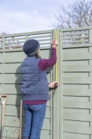 Woman marking three evenly spaced points towards the top of the fence post and one at the bottom