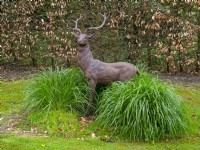 Deer Statue with grasses and beech hedge in Spring April