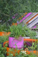 St. Mungo's Putting Down Roots Garden - RHS Chelsea Flower Show 2022 - Silver Medal - miniature urban park using recycled materials with circular orange and pink planter with water plants