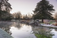 Pond with mist and reflections in January within the Bishop's Palace Garden, Wells, Somerset