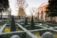 The East Garden at The Bishop's Palace Garden in Wells on a January morning, with evergreen hedges of Euonymus japonicus 'Green Spire' framing yew balls and slender pyramids.