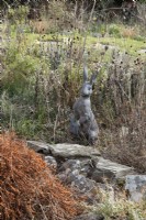 Alert Hare, bronze cast sculpture by Suzi Marsh, amongst dead border growth. February. 