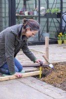 Woman measuring the depth of the hole for the wooden post to go in